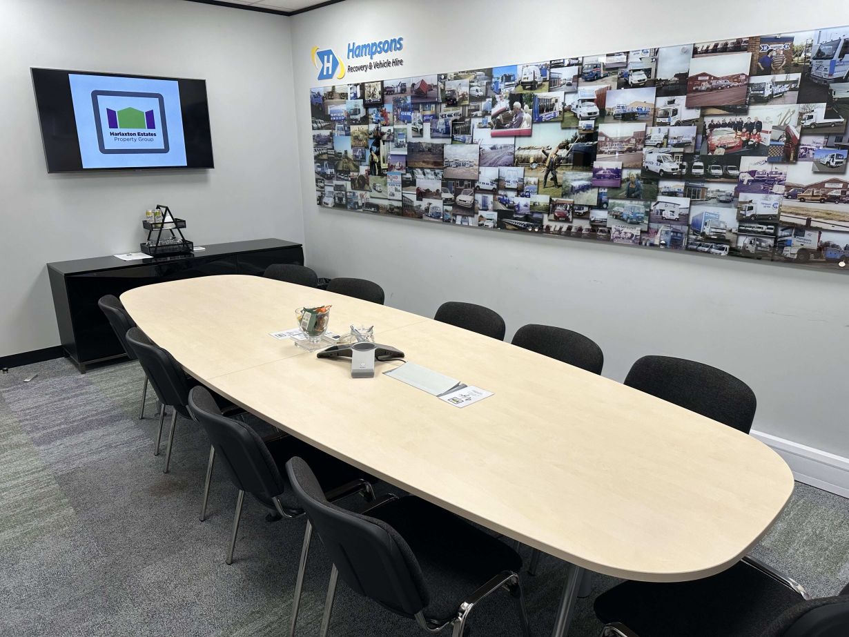 Functional and well-equipped meeting room in Harlaxton House with a large wall display of business achievements, designed for effective presentations and strategic discussions in a professional setting.