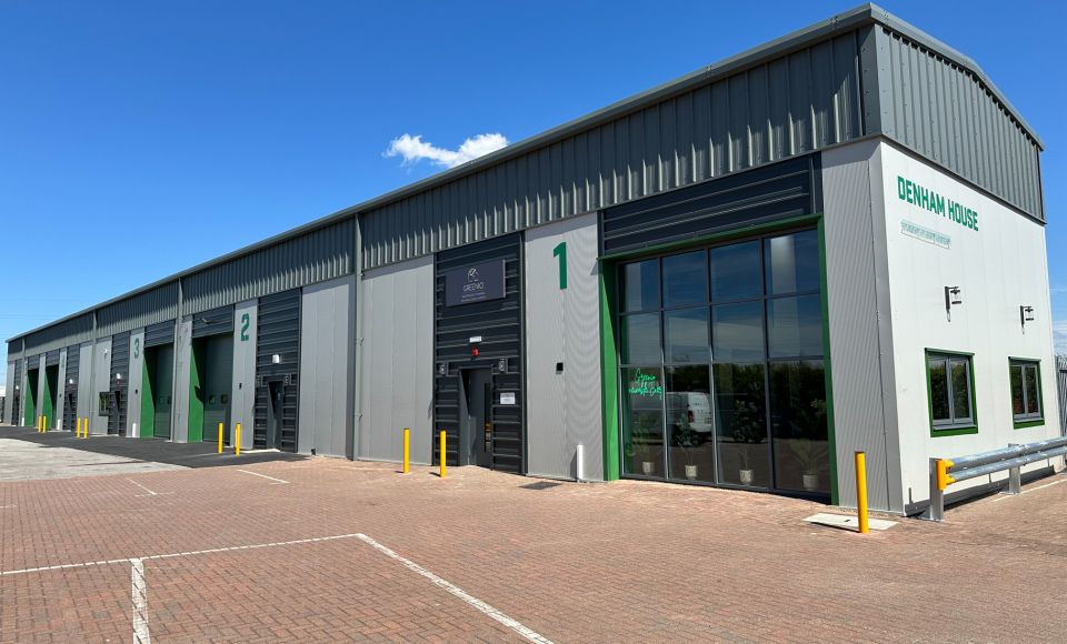 Exterior of a modern industrial building with multiple units, labelled 1 to 3, under a clear blue sky. The sign reads 'Denham House'