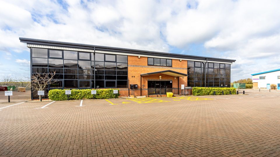 Exterior of Harlaxton House, a modern brick office building with large glass windows and an empty car park in front